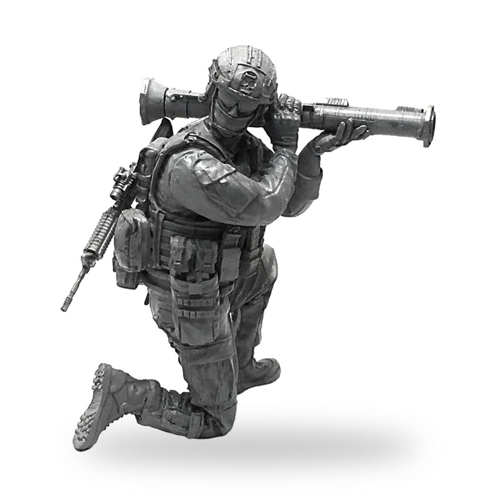 Unpainted US SEAL soldier in kneeling pose firing bazooka with rifle on back.