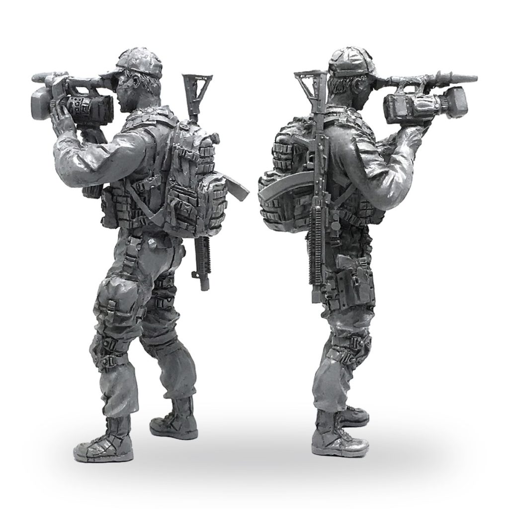 Unpainted 1/35 scale soldier figure holding video camera with backpack and rifle.