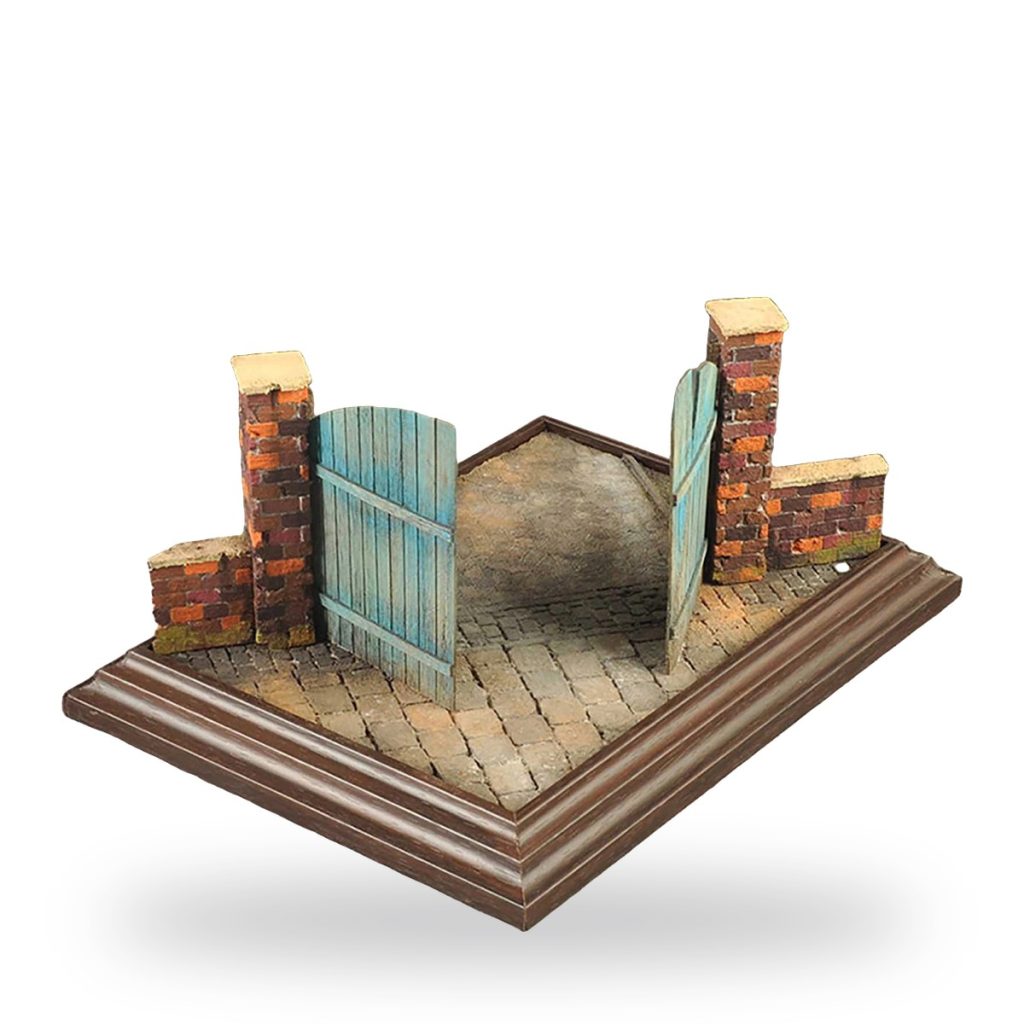 Unpainted miniature old brick wall with wooden gate on cobblestone base.