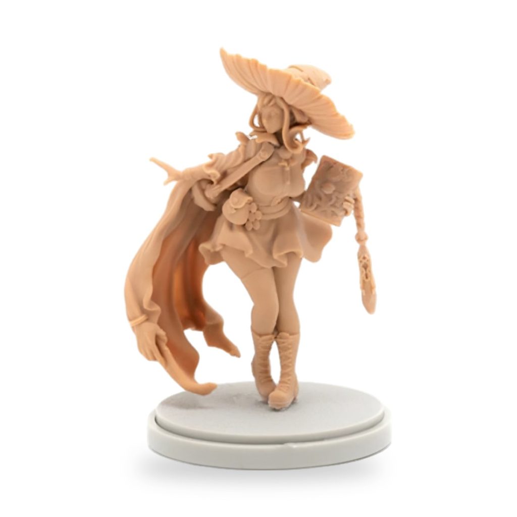 Unpainted resin figure of female mage with wide-brimmed hat and flowing cape holding spellbook.