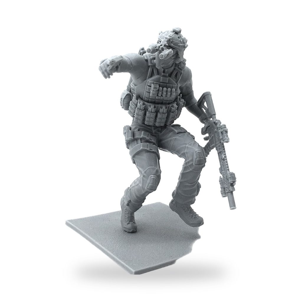 Unpainted resin miniature soldier in tactical gear holding rifle on base.