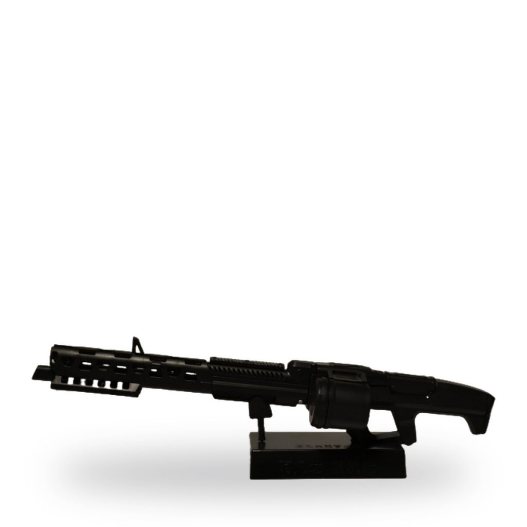 Black plastic machine gun model on display stand against white background.
